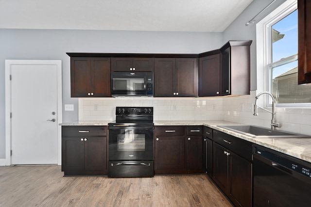 kitchen with dark brown cabinetry, black appliances, light wood-type flooring, and a sink