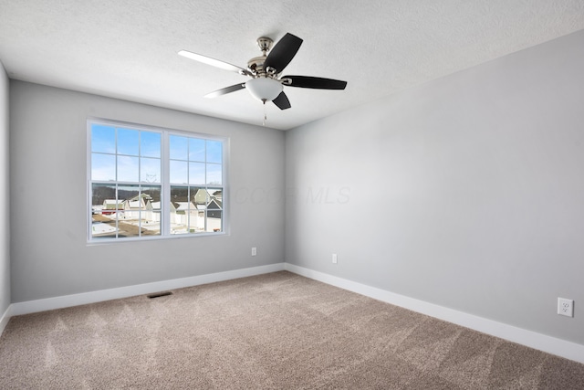 spare room with carpet, a textured ceiling, visible vents, and baseboards