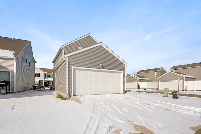 snow covered garage with a residential view and fence