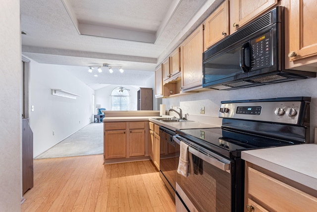 kitchen featuring electric range, a raised ceiling, light wood-style floors, black microwave, and a sink