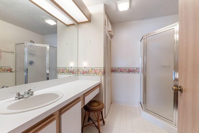 bathroom featuring a textured ceiling, a shower stall, and vanity