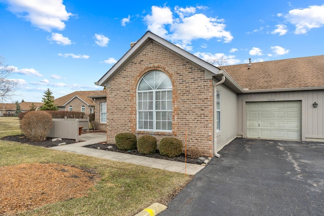 view of front of home with a garage, driveway, a shingled roof, fence, and brick siding