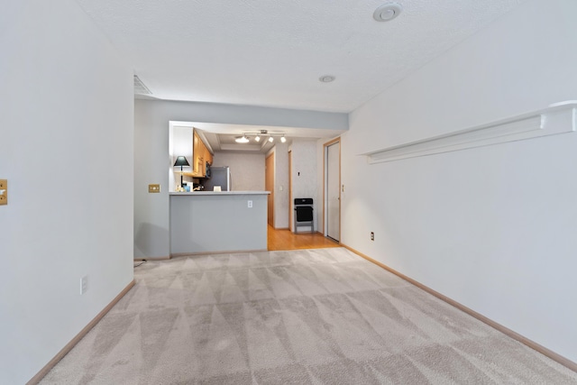 unfurnished living room with light carpet, visible vents, baseboards, and a textured ceiling