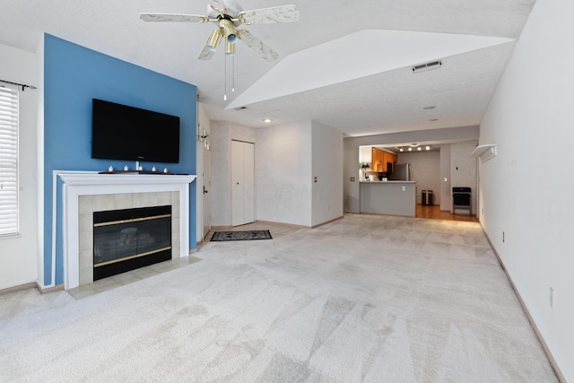 unfurnished living room featuring lofted ceiling, light carpet, a fireplace, visible vents, and baseboards