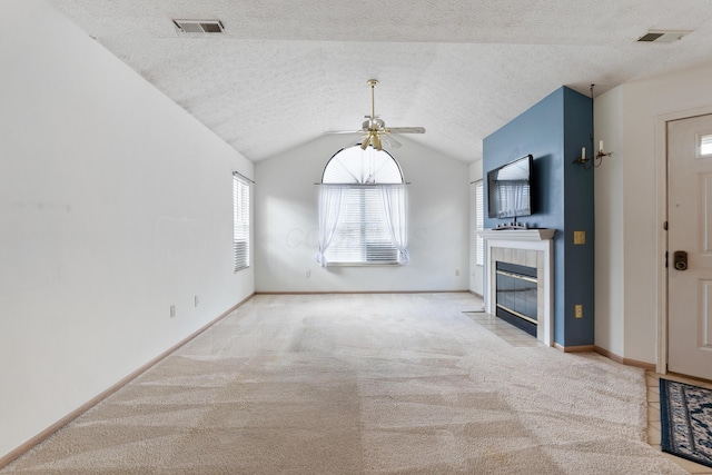 unfurnished living room featuring lofted ceiling, carpet, visible vents, and a tile fireplace