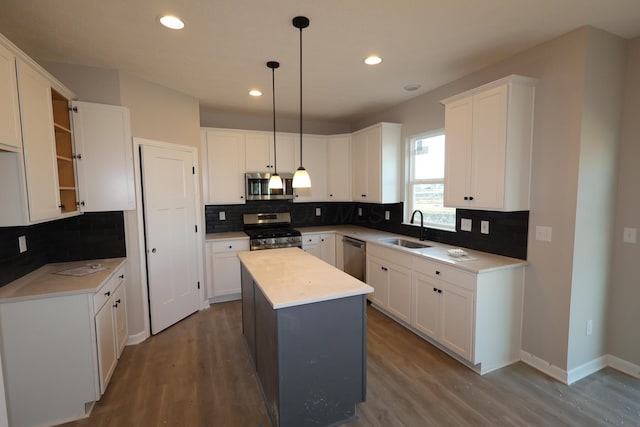 kitchen featuring stainless steel appliances, wood finished floors, a kitchen island, and a sink