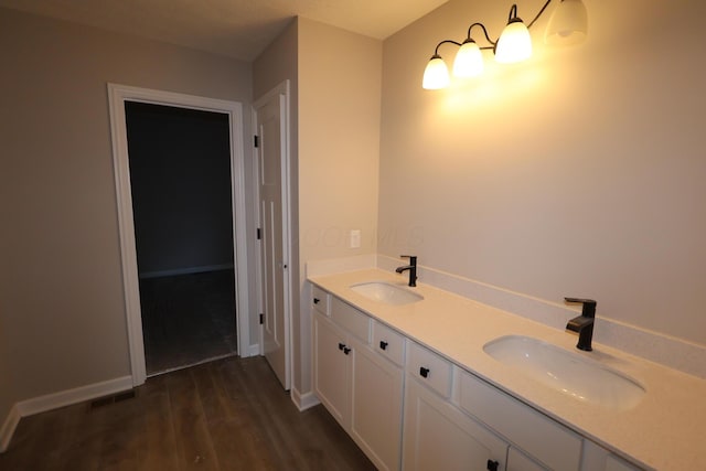 bathroom with wood finished floors, a sink, and baseboards