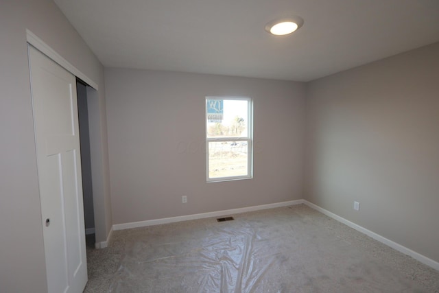 unfurnished bedroom with light carpet, a closet, visible vents, and baseboards