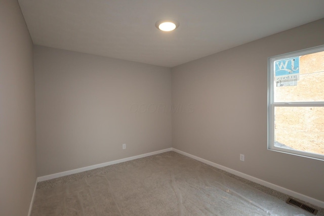 empty room with baseboards, visible vents, and light colored carpet