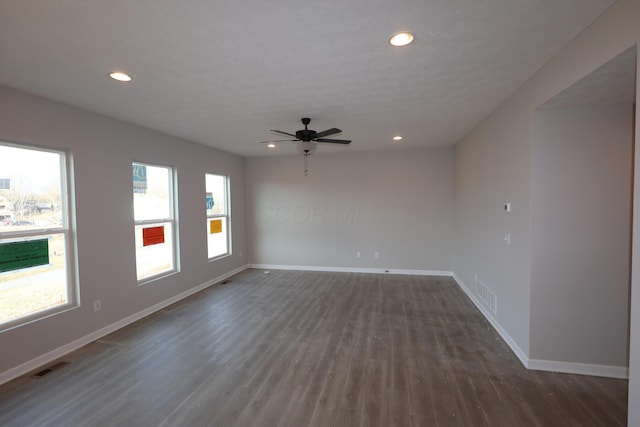 empty room featuring dark wood-style floors, recessed lighting, visible vents, and baseboards