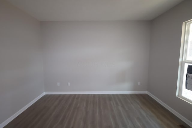 empty room featuring dark wood-style flooring and baseboards