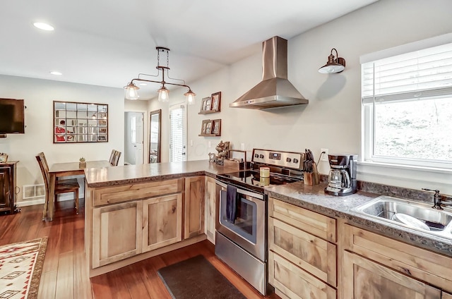 kitchen featuring sink, wall chimney exhaust hood, kitchen peninsula, pendant lighting, and stainless steel range with electric stovetop