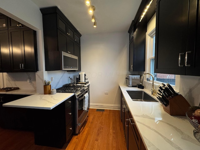 kitchen with light stone counters, stainless steel appliances, light hardwood / wood-style flooring, and sink