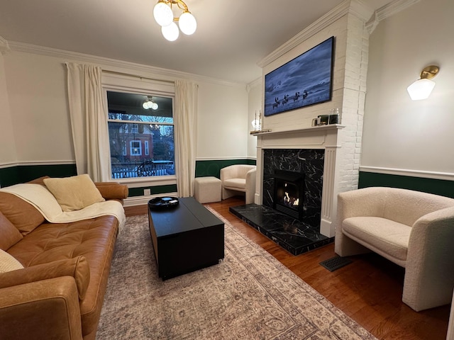 living room with hardwood / wood-style flooring, ornamental molding, and a premium fireplace