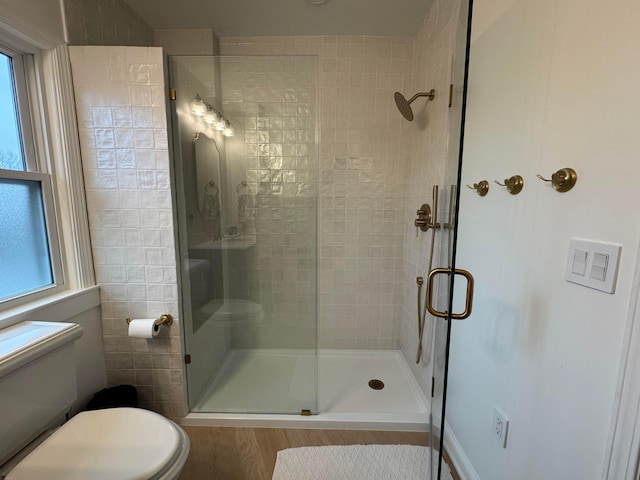 bathroom featuring toilet, a shower with shower door, and wood-type flooring