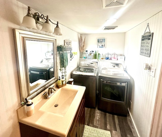 laundry room with washing machine and dryer, wood walls, sink, and dark hardwood / wood-style floors