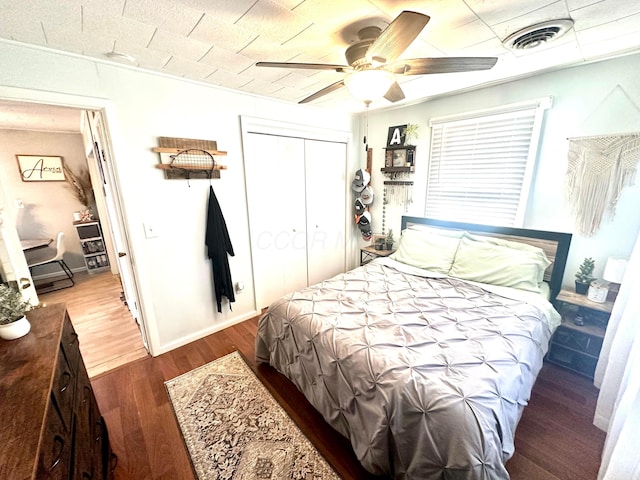 bedroom with ceiling fan, a closet, and dark wood-type flooring