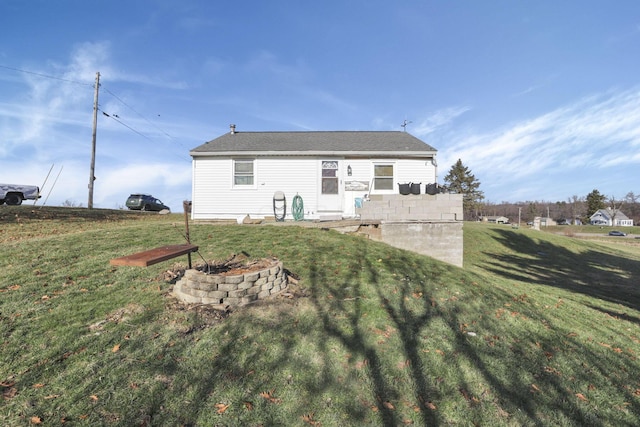 rear view of property featuring a yard, a patio, and a fire pit