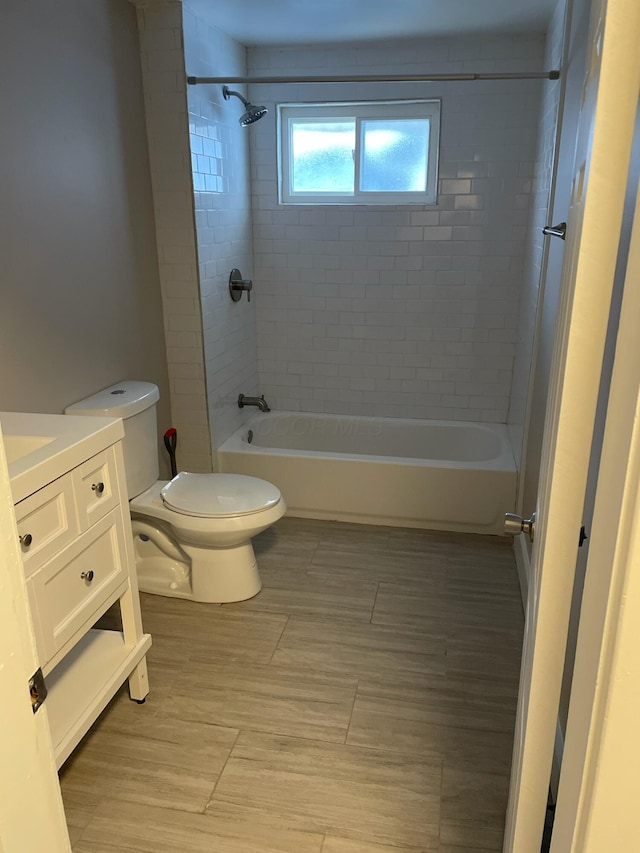 full bathroom featuring vanity, tiled shower / bath, and toilet