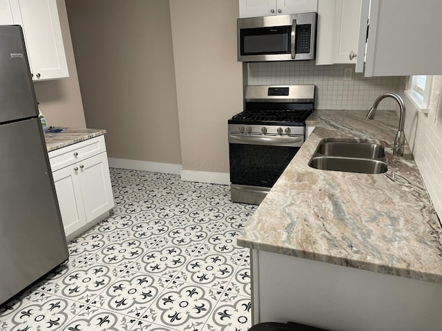 kitchen featuring appliances with stainless steel finishes, light stone countertops, sink, and white cabinets