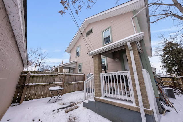 snow covered back of property with central AC unit