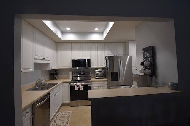 kitchen featuring white cabinetry, sink, a raised ceiling, and appliances with stainless steel finishes