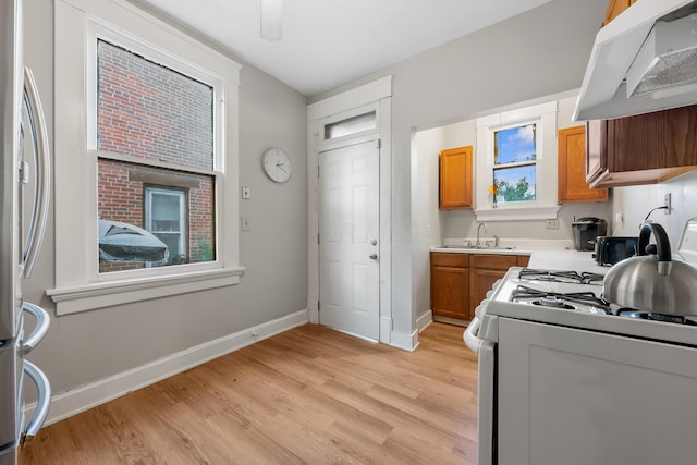 kitchen featuring sink, white gas stove, ventilation hood, stainless steel refrigerator, and light hardwood / wood-style floors