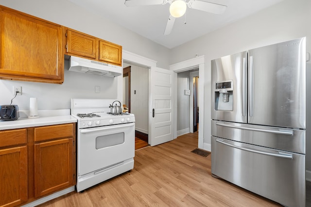 kitchen with stainless steel refrigerator with ice dispenser, white gas stove, ceiling fan, and light hardwood / wood-style flooring