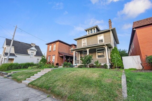 traditional style home featuring covered porch, a chimney, and a front yard