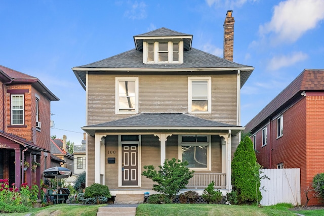 traditional style home with a porch, fence, a chimney, and a shingled roof