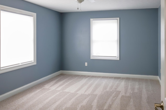 carpeted spare room featuring a ceiling fan and baseboards