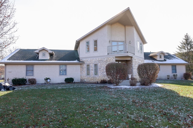 rear view of house with a lawn and a balcony