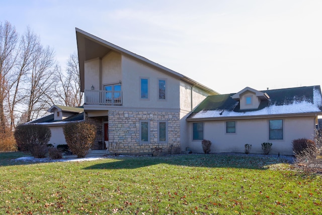 back of house featuring a balcony and a lawn