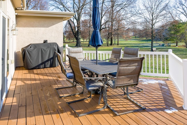 wooden deck with outdoor dining space, a yard, and a grill