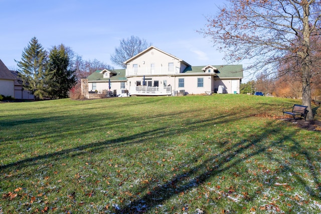 rear view of property featuring a balcony and a yard