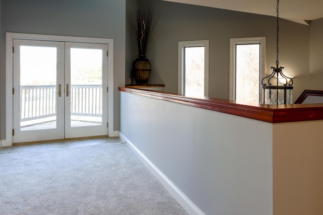 corridor featuring light carpet, plenty of natural light, french doors, and lofted ceiling