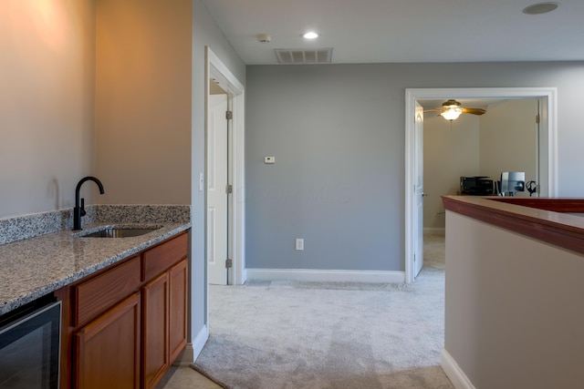 interior space with light stone countertops, visible vents, a sink, wine cooler, and light carpet