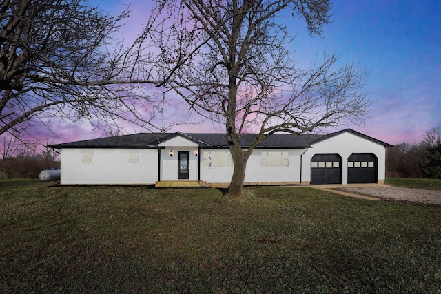 ranch-style home with a garage and a lawn