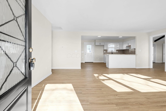 unfurnished living room featuring sink and light hardwood / wood-style floors