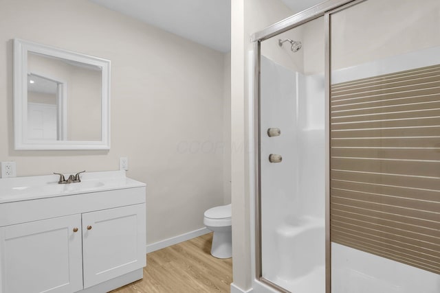 bathroom featuring hardwood / wood-style flooring, vanity, toilet, and a shower with door