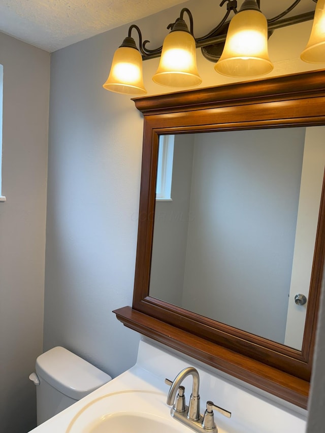 bathroom featuring a textured ceiling, toilet, and sink