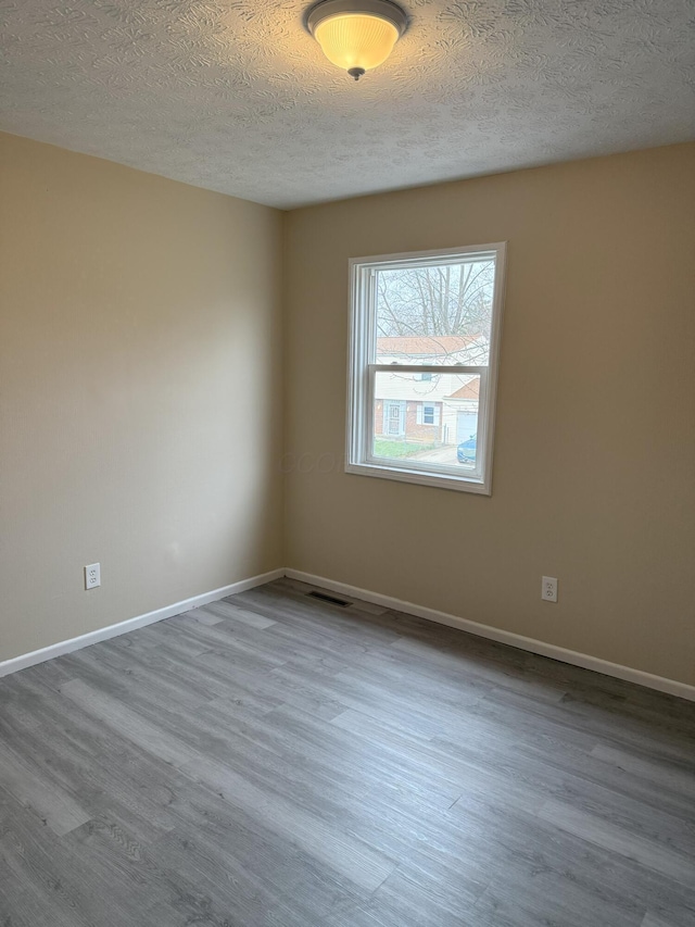 unfurnished room with wood-type flooring and a textured ceiling