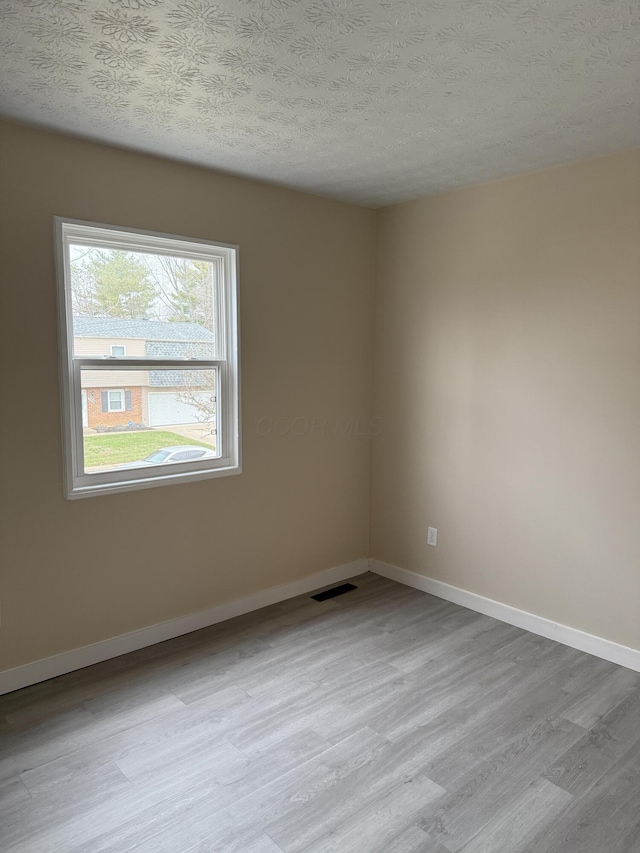 unfurnished room featuring a textured ceiling and light hardwood / wood-style flooring