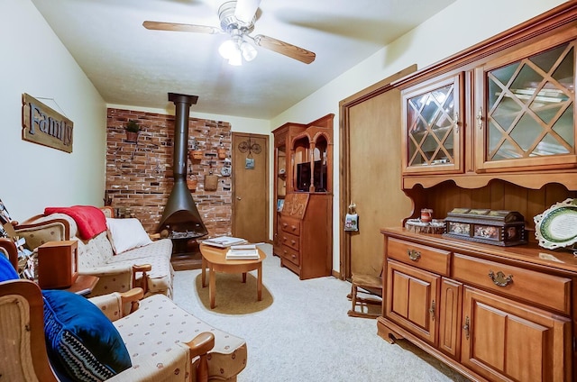 interior space featuring light colored carpet, a wood stove, and ceiling fan