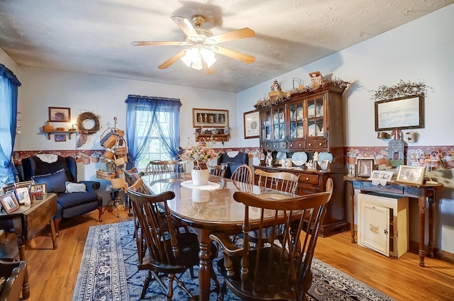 dining area with ceiling fan, light hardwood / wood-style flooring, and a textured ceiling