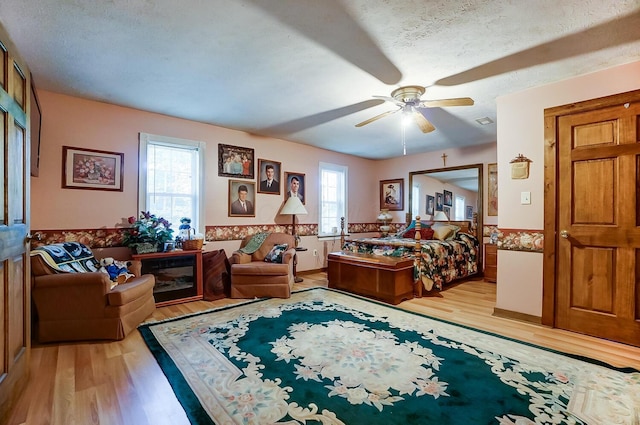 bedroom featuring ceiling fan, light hardwood / wood-style floors, and a textured ceiling