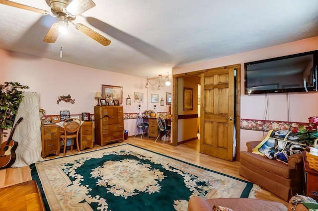 living room featuring ceiling fan with notable chandelier and light hardwood / wood-style floors