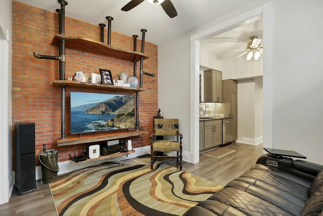 living room featuring ceiling fan, sink, and light wood-type flooring