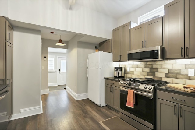 kitchen featuring appliances with stainless steel finishes, tasteful backsplash, hanging light fixtures, and dark hardwood / wood-style floors