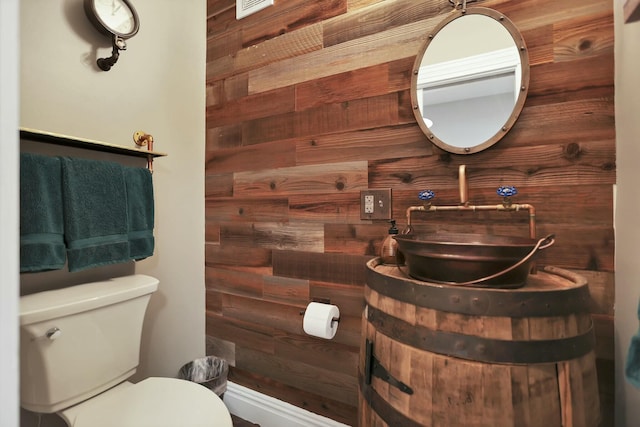 bathroom with vanity, wood walls, and toilet